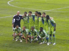 Eleven Soccer Players Wearing Green Jerseys And Green Shorts Posing In Two Rows On A Grass. Starting Players Before A 2009 Sounders Fc Match - Seattle Sounders Fc, Transparent background PNG HD thumbnail